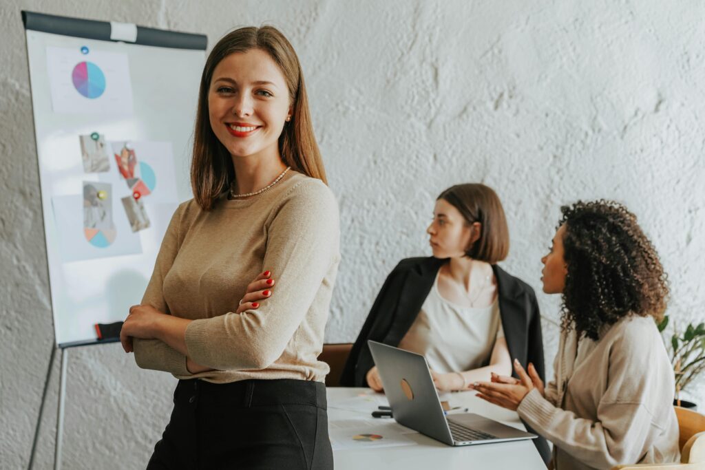 Sales rep smiling while a team holds a presentation on a whiteboard